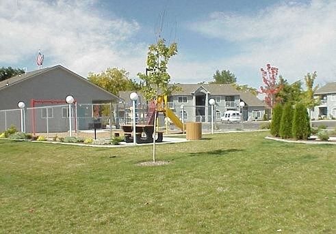 a yard with a swing set and houses in the background